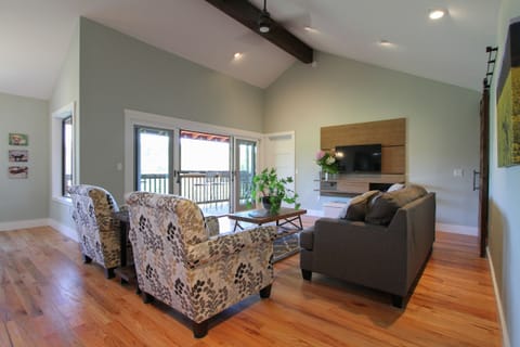 Living room, high ceiling, fan, tv panel, door to deck