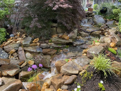 Beautiful gardens include a waterfall & creek along the side of the property.