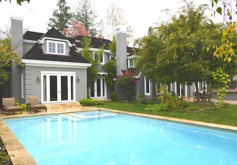 Backyard swimming pool surrounded by lush green trees.
