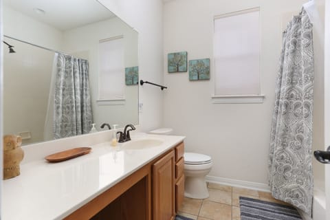 Full bathroom with combined tub shower and single vanity sink with knee space.