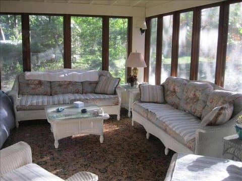 Cozy sunroom with wicker funiture and side panels covering screen as needed