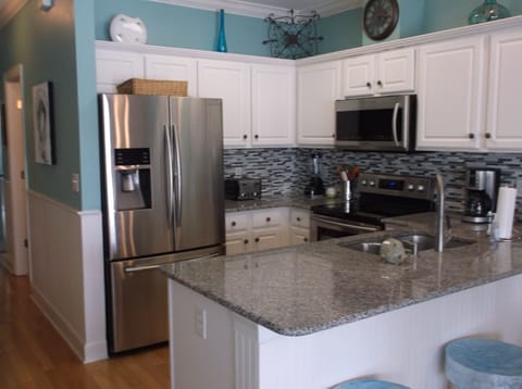Kitchen with granite countertops, glass back splash & stainless appliances.