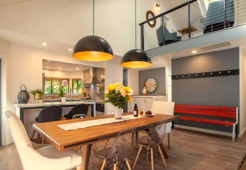 Stylish open-concept dining area with a warm wood table, modern pendant lights, and views into the kitchen and loft. Perfect for shared meals, entertaining, and enjoying the home’s bright, contemporary design.