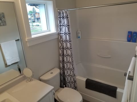 A bright, clean and fresh, full bathroom with a combination tub and shower.