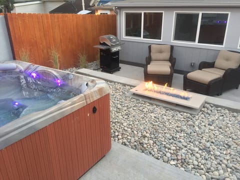 Private spa-like backyard: hot tub, fire table, and gas grill