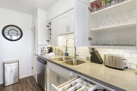 The fashionable kitchen has a coffee machine, 2 sinks and cooking utensils.