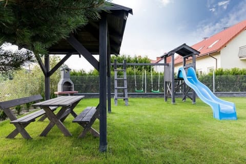 An outdoor area with a wooden gazebo, a picnic table, and a playground set, perfect for family gatherings and outdoor play.