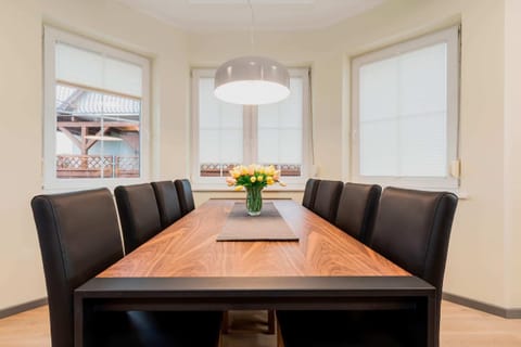 A dining area connected to a living room, featuring a wooden table with four chairs and an open, spacious design.