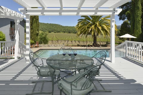 Outdoor dining in the shade overlooking vineyard and pool.