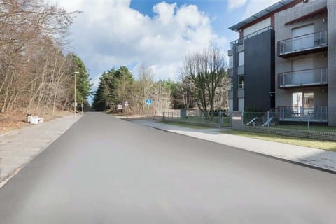 A scenic street view with modern apartment buildings and surrounding greenery, creating a serene environment.