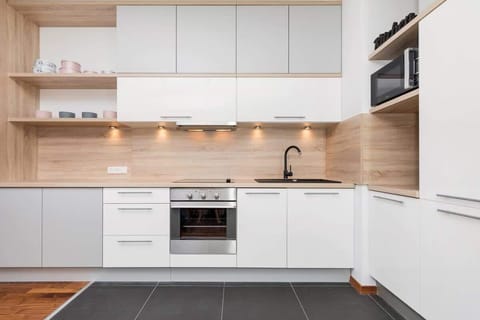 Bright kitchen annex with white furniture and wooden worktop. High-quality appliances microwave, oven and induction hob.