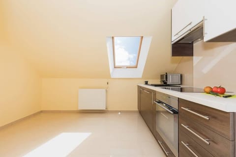 A second kitchen located in the attic. Furniture in brown and white. The kitchen has an oven.