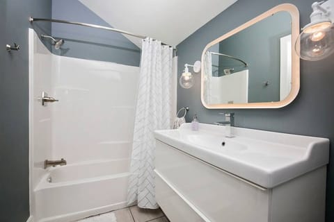 Bright and stylish bathroom with a full tub, glowing vanity, and sleek finishes.