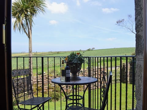 A table and chairs placed outside the living room makes a great place to enjoy the view and a glass of wine | Coachmans Cottage, White Cross, near Newquay