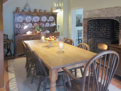 A grand farmhouse kitchen style table and a woodburning stove complement the traditional cottage furnishings | The Coach House - Berrington House, Tenbury Wells