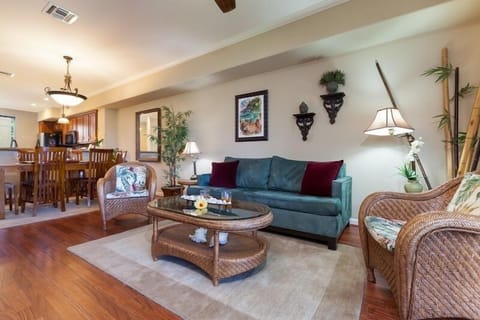 - Relax in the inviting living area with plush sofa and tropical inspired wicker furnishings - Warm wood floors and neutral tones create a calming welcoming atmosphere - Open layout flows into dining space perfect for shared meals and conversation
