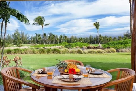 - Outdoor dining table set with tropical fruit centerpiece and refreshing juice glasses - Sweeping golf course views framed by swaying palm trees and vibrant blue skies - Perfect setting for relaxed breakfasts or evening meals with nature all around