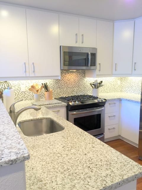 Brand-new kitchen with slab granite counter top + glass and stone backsplash