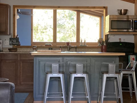Kitchen island with view through sunroom  out to beautiful woods.

