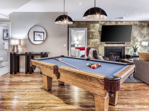 Pool table with living room in background along with fireplace & 75" OLED TV.