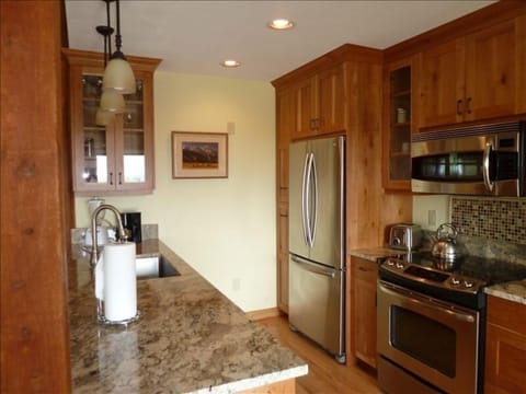 Kitchen with new stainless appliances, cherry cabinets, and granite countertops.