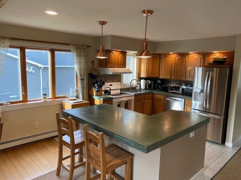 Kitchen, with concrete countertops, large island with stool, updated appliances.