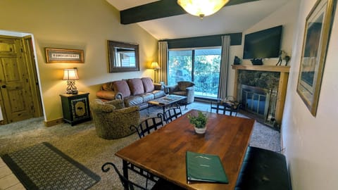 Living room with sofa bed, wood fireplace, dining table, and balcony w/ gas BBQ