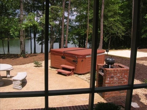View of hot tub, lake and sand area through screened in porch