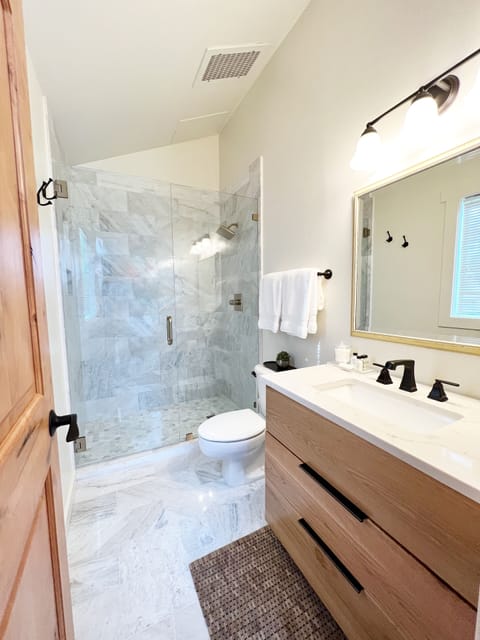 Newly remodeled bathroom with marble walk-in shower, vanity & toilet