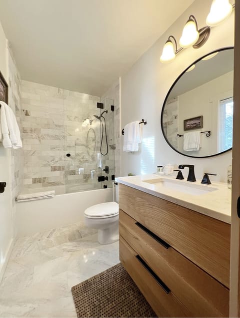 Newly remodeled full marble guest bath with soaking tub, vanity and toilet