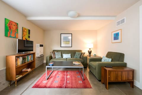 Living room w/ queen sleeper sofa, club chair, tables, bookshelf & 60" TV. 
