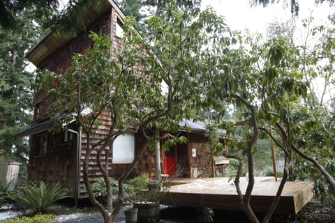Cabin with large deck nestled in the trees.