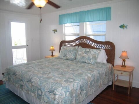 Master bedroom w/ king bed, paddle fan, A/C, & door to front porch. Ground floor