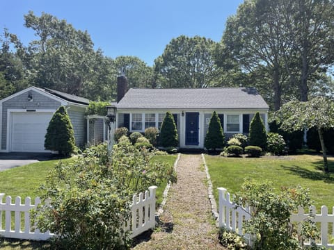 A cobblestone lined walk, white picket fence, and well maintained landscaping.