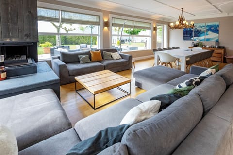 Large living / dining space with comfy couches by the fireplace and lake views