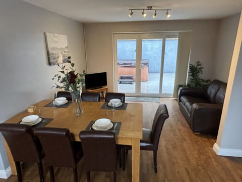 Open plan dining area and living room with smart tv leading to hot tub