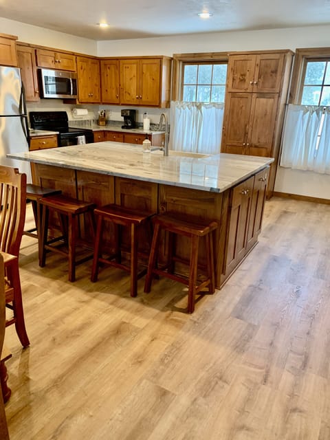 Large island with granite countertops, apron sink and seating for four.