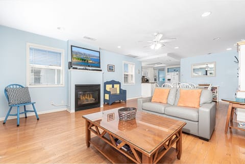 The main living area includes TV, fireplace, leather sofa with queen pullout bed, dining table with seating for 6, and doors that lead to the ocean view patio.