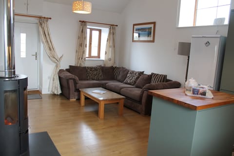 Open plan lounge with wood burning stove, front door & kitchen.