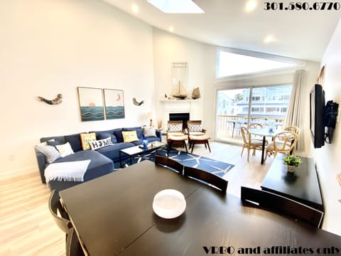 Living area with large sectional, flat panel HDTV, fireplace and 2 dining tables