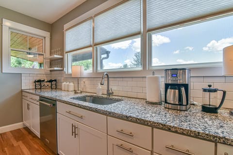A modern kitchen with white cabinets, granite countertops, and views of the sky