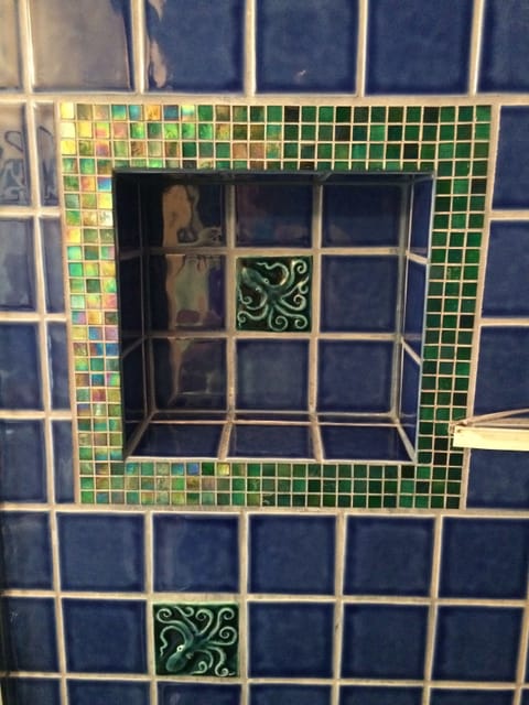 Recessed shelf in walk-in custom tile shower adorned with whimsical octopus tile
