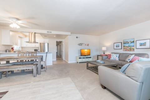 Vantage point from the unit's entry area toward living room and TV. Carpeting throughout this upper unit.