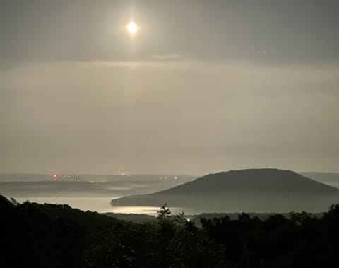 Peaceful night, moon shining through the clouds and the lights across the lake.