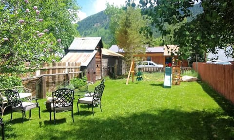 Large backyard equipped with loan chairs, firepit, grill and a nice playground.