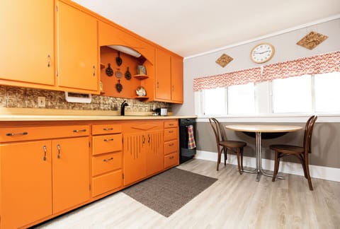 Sunny kitchen is fully stocked with silverware, plates, glasses and cups.