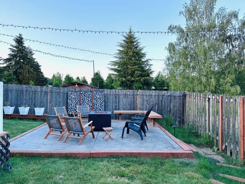 Outdoor fire-pit area with 6 comfortable chairs & bench. Landscape lighting.