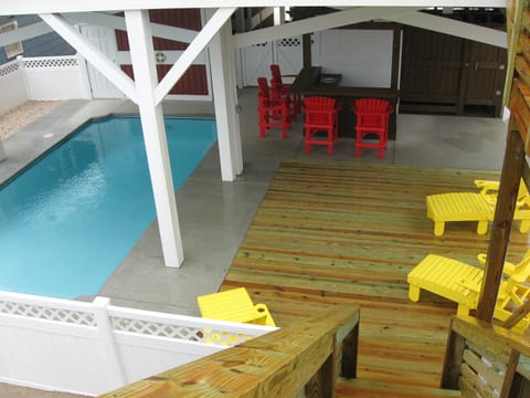 Pool area, with decking, Tiki bar, outdoor shower/ charge area, and deck chairs