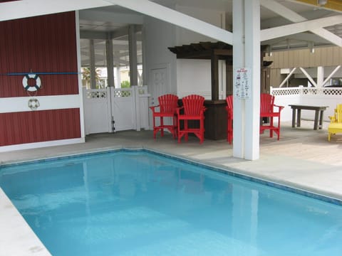 View of the ground level with pool, Tiki bar, and chairs.