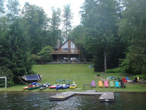 View from the lake of house, chairs, fire pit and lake toys